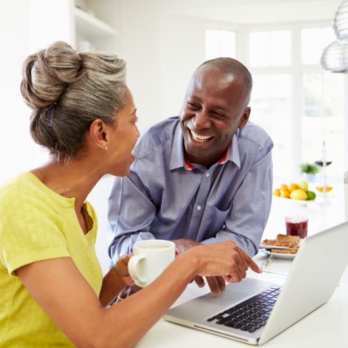 Mature,African,American,Couple,Using,Laptop,At,Breakfast