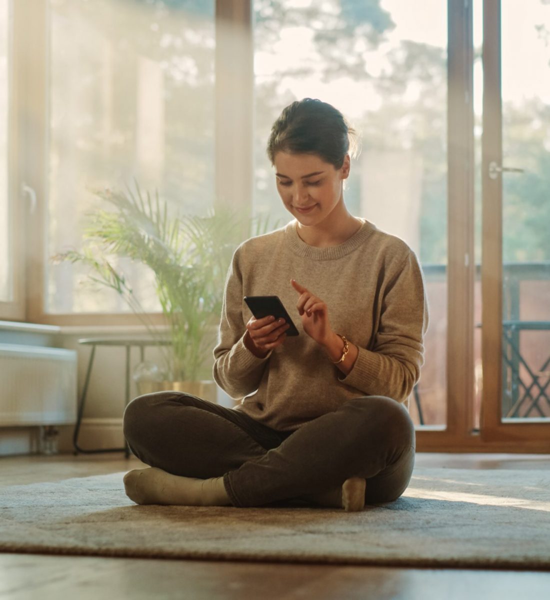 Smiling,Young,Woman,Using,Smartphone,At,Home,,Does,Remote,Work. Smiling,Young,Woman,Using,Smartphone,At,Home,,Does,Remote,Work.