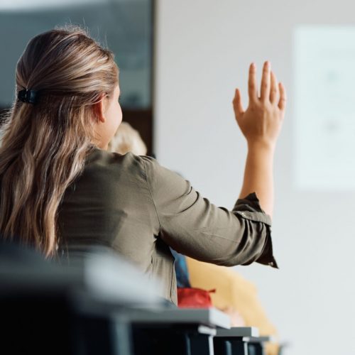 Back,View,Of,Student,Raising,Her,Hand,To,Answer,Teacher's